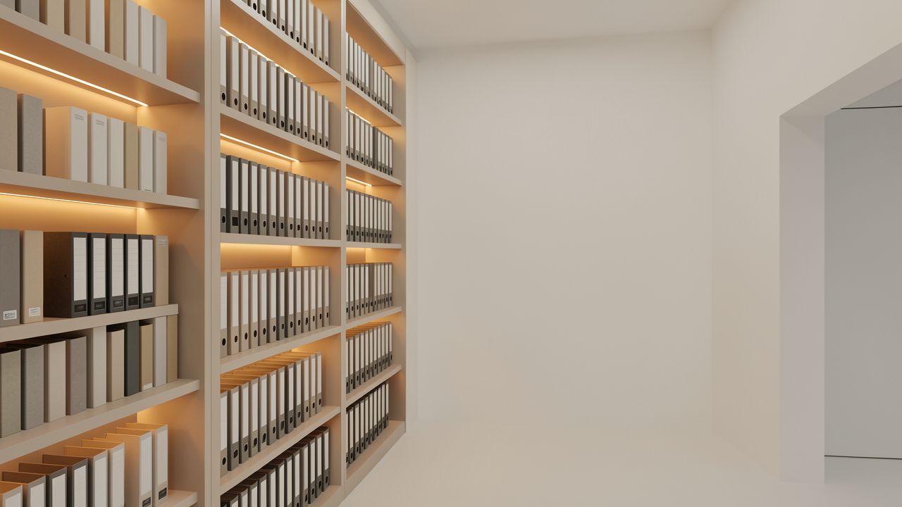 Ein langes Archivregal voller Ordner, warm beleuchtet